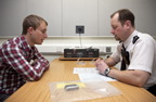 photograph of a man being interviewed by a policeman